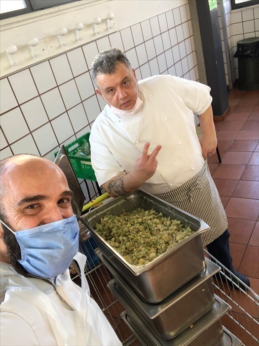 sorrisi sotto le mascherine nella cucina Caritas