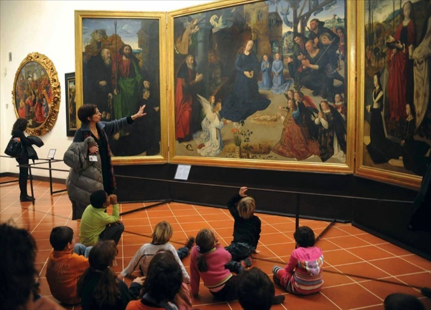 bambini seduti davanti al trittico Portinari del pittore fiammingo Hugo