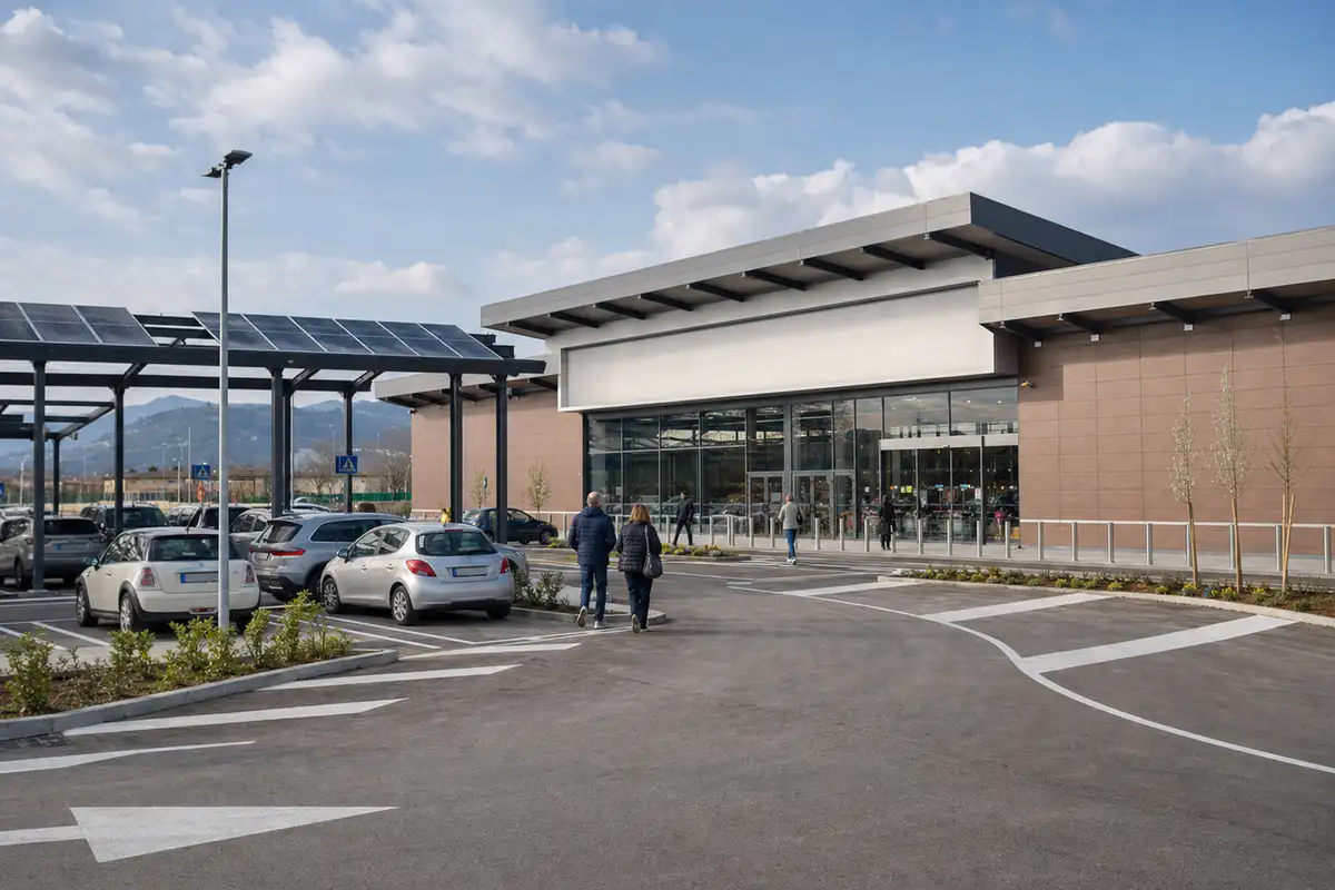 Ingresso di un supermercato moderno con parcheggio, auto e pensiline con pannelli solari