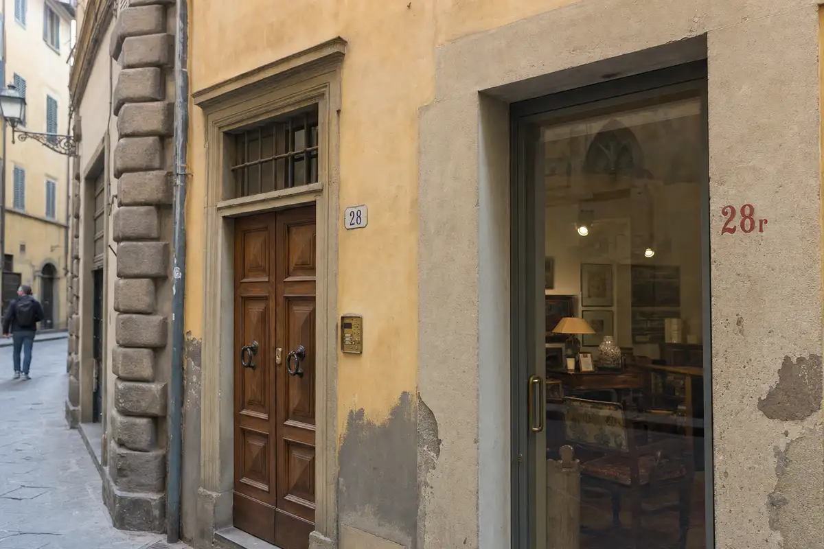 Due ingressi su strada a Firenze con civico 28 su targa blu e civico rosso 28r accanto a una vetrina